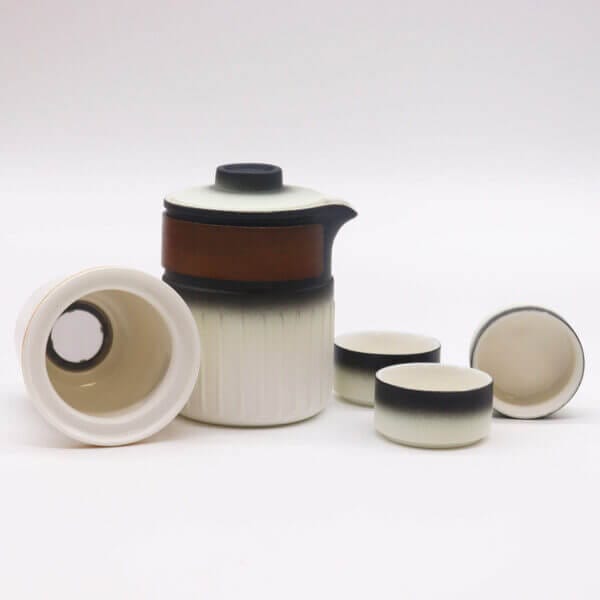 A ceramic tea set with a lidded teapot and three cups, all in a white and black gradient design, displayed on a plain white background.