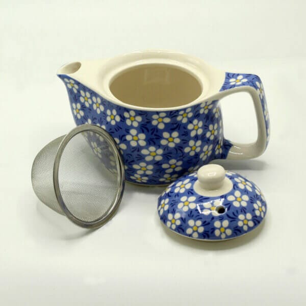A blue and white floral teapot with a handle, shown with its lid and a metal mesh infuser placed beside it on a white background.