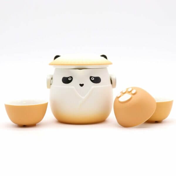 A tea set featuring a panda-shaped teapot with a lid and two matching cups, all with a beige and white color scheme and paw print details.