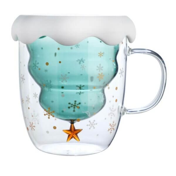 Glass mug with a snowflake design and an inverted Christmas tree inside. The tree is teal, topped with a white snow cap, and adorned with a gold star at the bottom.